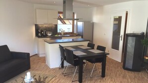 A modern kitchen with white cabinets, a central island, and a dining area with a black table and chairs.