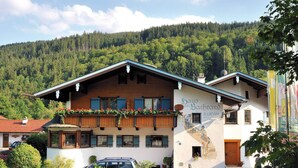 A traditional Alpine-style building with a wooden facade, a balcony with flowers, and a sign indicating it is a guesthouse.