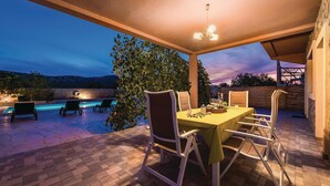 Eine Terrasse im Freien mit Esstisch, Stühlen und einem Pool.