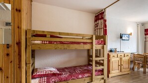 A bunk bed with a wooden frame and red bedding, a wooden desk with a chair, and a television on the wall. - South-Facing Studio Near Aquatic Area, Pets Allowed (La Clusaz)