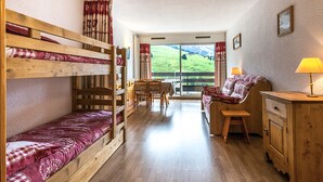 A cozy room with bunk beds, a desk, a chair, and a couch. - South-Facing Studio Near Aquatic Area, Pets Allowed (La Clusaz)