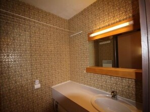 A bathroom with patterned wallpaper, a white sink, and a mirror with a wooden frame.