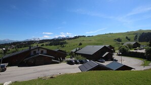 A rural village with traditional wooden houses, a parking area, and a clear view of distant mountains. - Bright cabin studio in Les Saisies, ski-in/ski-out, balcony, 5 sleeps (Hauteluce)