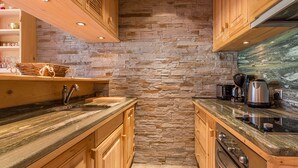A kitchen with wooden cabinets, a stone wall, and a granite countertop.