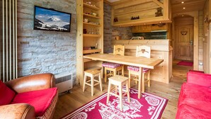 A cozy room with a stone wall, wooden furniture, and a red rug.