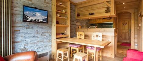 A cozy room with a stone wall, wooden furniture, and a red rug.
