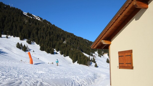 A snow-covered slope with a wooden building and a person skiing. - Stunning 4-Room Mezzanine with Parking and Pets Allowed (Villard-sur-Doron)