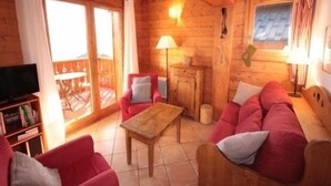 A cozy log cabin interior with a wooden ceiling, a sofa set, a television, and a dining table. - Stunning 4-Room Mezzanine with Parking and Pets Allowed (Villard-sur-Doron)