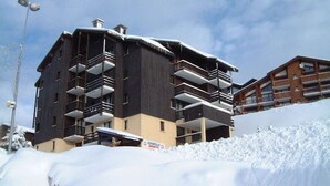 Un immeuble à plusieurs étages doté de balcons, entouré de neige.