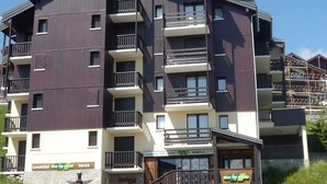 Un immeuble à plusieurs étages doté de balcons, d’une enseigne indiquant le lieu, et d’une entrée bien visible.
