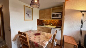 Una cocina compacta con armarios de madera, microondas y salpicadero de azulejos.