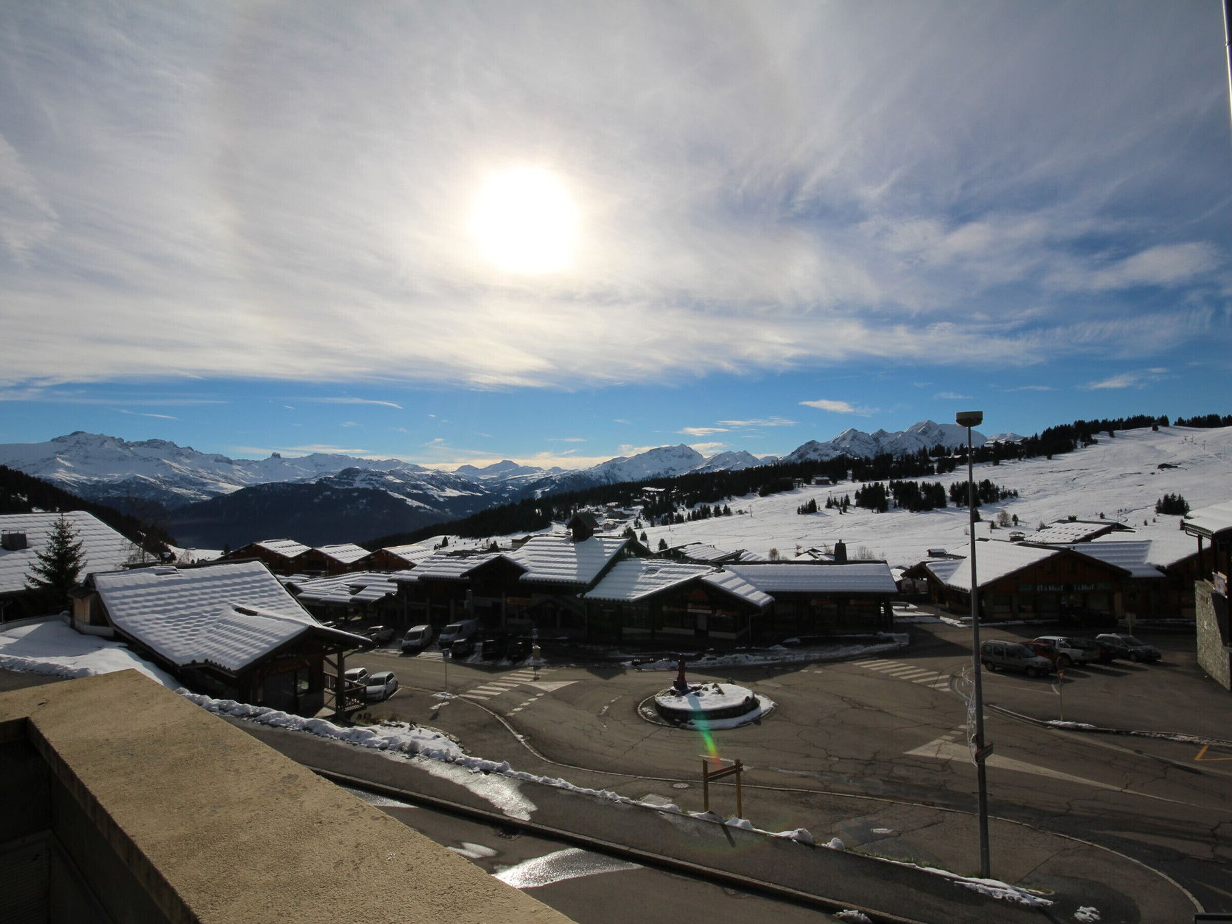 A snow-covered village with buildings and a clear view of mountains in the background.