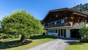 Ein zweigeschossiges Holzhaus mit Balkon, einem Schotterweg und einem gepflegten Rasen.