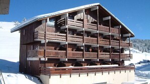 A multi-story wooden chalet with balconies, situated on a snowy mountain. - Les Saisies - Studio Cabin 4 People, South (Les Saisies)