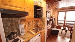 Une cuisine compacte avec des meubles en bois, une machine à café, un évier et un lave-vaisselle.