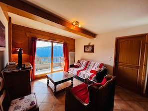 A cozy living room with a wooden ceiling, a sofa, a table, and a television.
