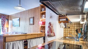 Een keuken met houten kastjes, een roestvrijstalen spoelbak en een raam met uitzicht op een besneeerd landschap.