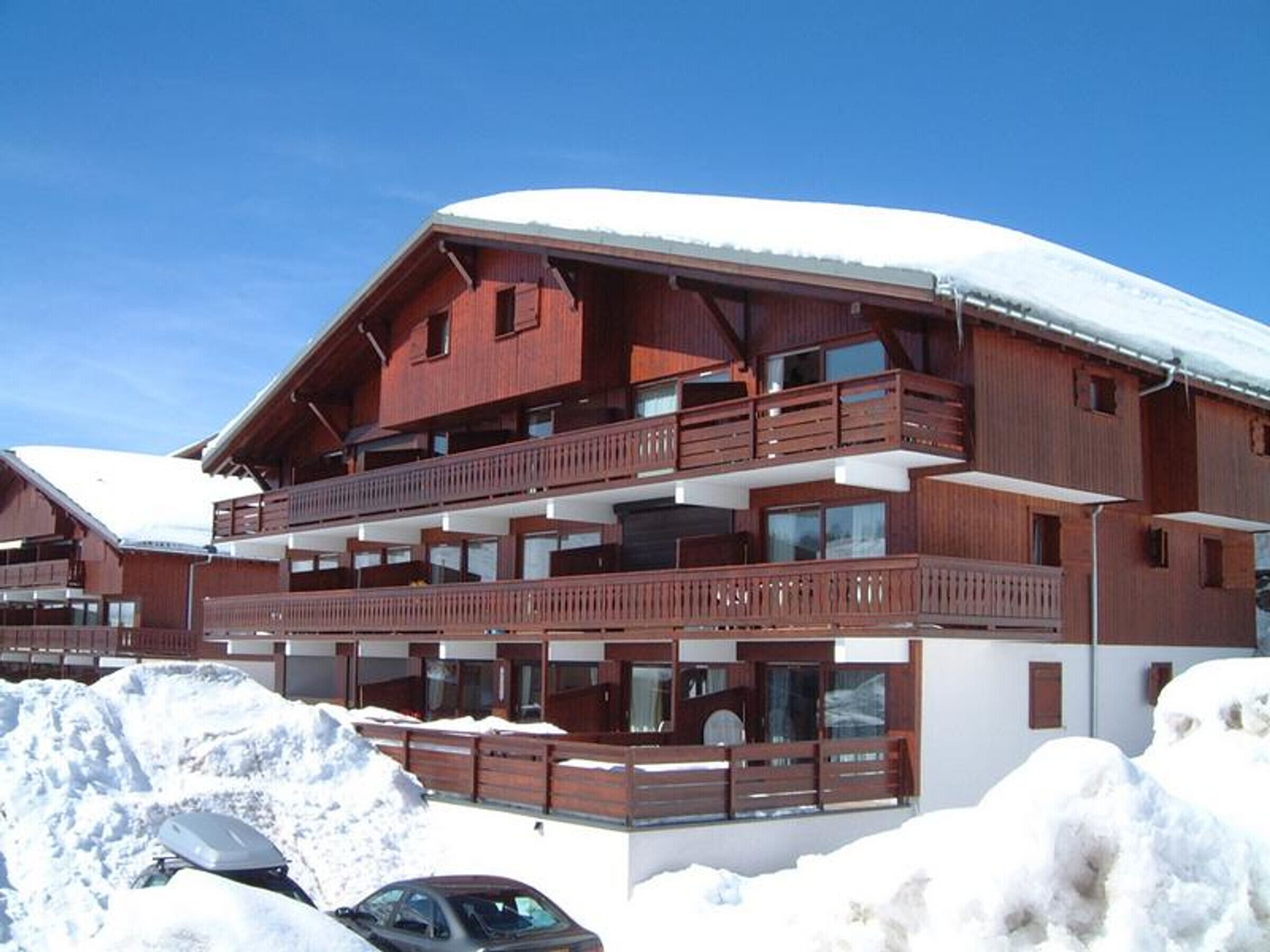 A multi-story wooden chalet with balconies, surrounded by snow.