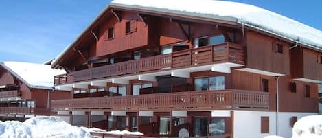 Un chalet en bois à plusieurs étages, doté de balcons et entouré de neige.