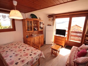 A cozy room with a bed, a wooden cabinet, a small table, and a television.