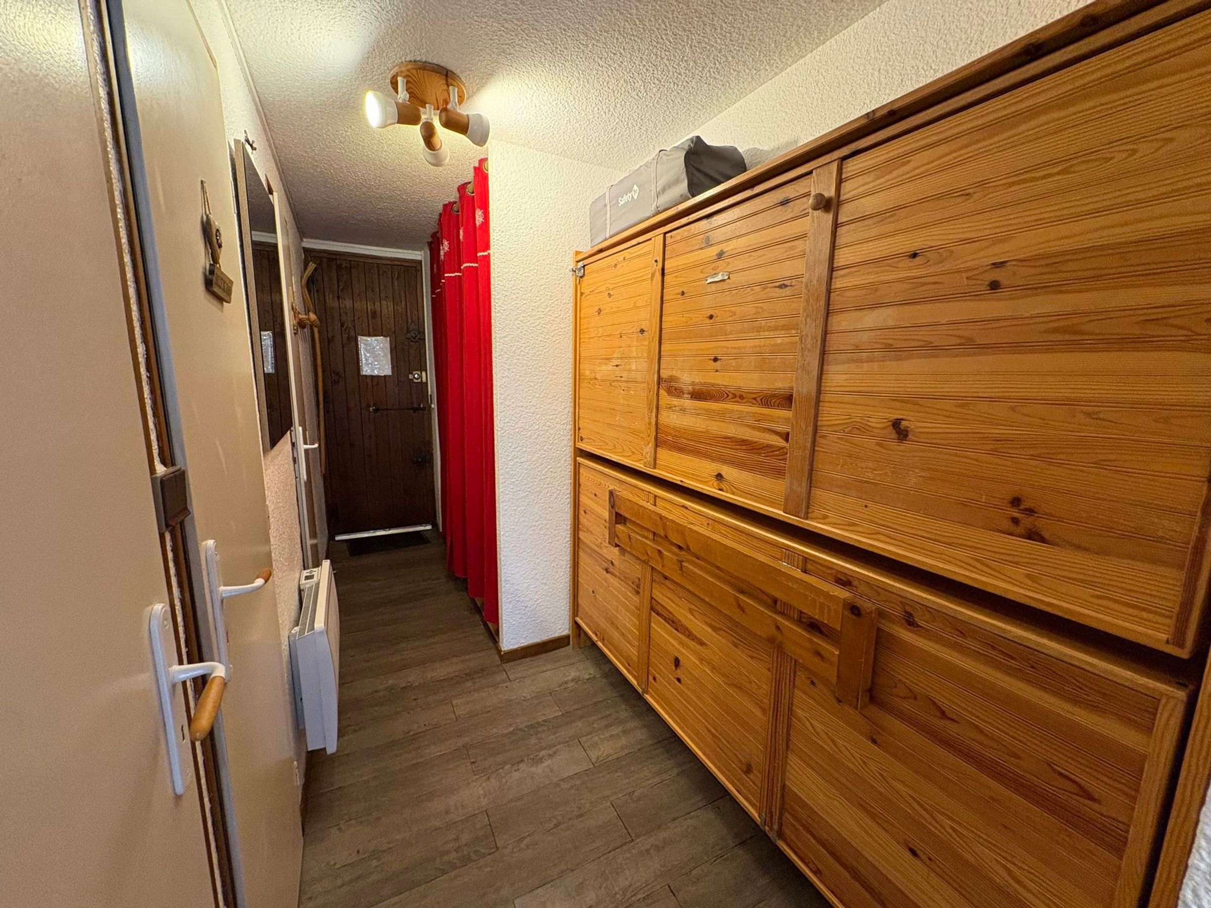 A hallway with a wooden wardrobe, a door with a handle, and a ceiling light fixture.