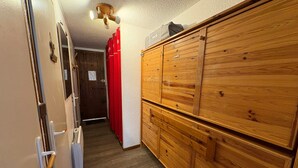 A hallway with a wooden wardrobe, a door with a handle, and a ceiling light fixture. - Cozy cabin studio for 4 at Les Saisies, pets allowed (Les Saisies)