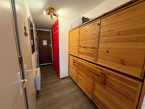 A hallway with a wooden wardrobe, a door with a handle, and a ceiling light fixture. - Cozy cabin studio for 4 at Les Saisies, pets allowed (Les Saisies)