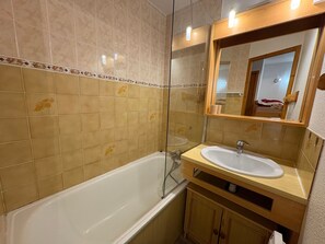 A bathroom with a bathtub, a sink, and a mirror.
