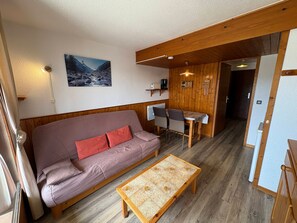 A cozy living room with a sofa, a coffee table, and a dining area with a table and chairs.