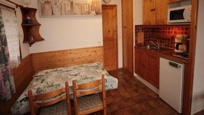 A compact kitchen with wooden cabinets, a microwave, and a small refrigerator. - Studio cabin with large terrace and ideal location (Les Saisies)