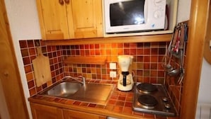 A compact kitchen with a microwave, coffee maker, and stove. - Studio cabin with large terrace and ideal location (Les Saisies)