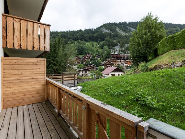 A wooden deck with a view of a village and mountains in the background.
