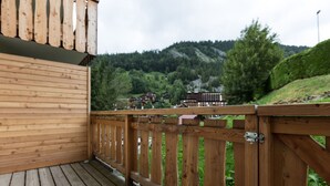 A wooden deck with a view of a mountainous landscape and buildings in the background. - Central apartment, 4 pers, Parking, Wifi (La Clusaz)