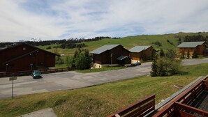 A rural setting with several wooden buildings, a paved road, and a car parked in front.