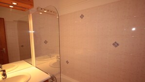 A bathroom with a white sink, mirror, and bathtub.
