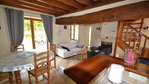 Un accogliente soggiorno con soffitto in legno, un tavolo da pranzo con sedie, un divano e un angolo cottura con una macchina da caffè.