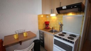 A compact kitchen with a stove, sink, and a coffee maker.