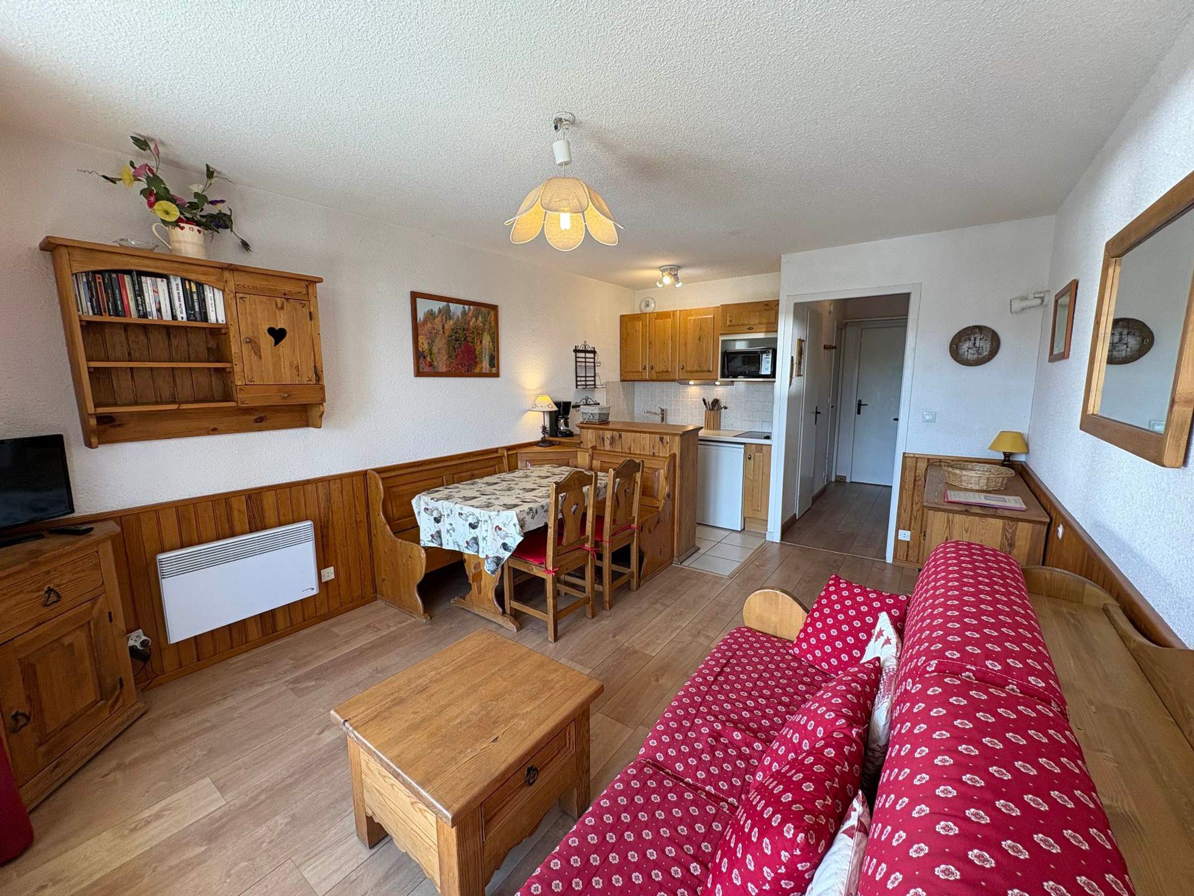 A cozy living room with a sofa, a dining table, and a kitchen area with wooden cabinets and a microwave.