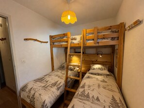A bunk bed room with a ladder, a small table, and a hanging light fixture. - Apartment with pets, mountain view - 5 guests (Les Saisies)