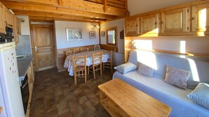 Un intérieur de chalet chaleureux comprenant un coin repas, une kitchenette et un canapé-lit.
