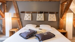A bedroom with a wooden ceiling, a bed with white bedding, and four bedside lamps.
