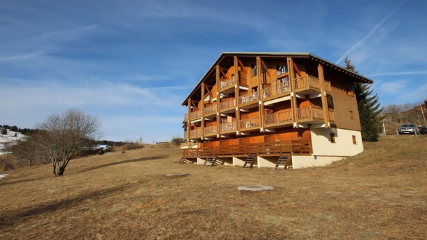 A multi-story wooden chalet with balconies, set in a grassy area with a clear sky. - Cozy studio in Les Saisies, 5 pers, south balcony (Les Saisies)