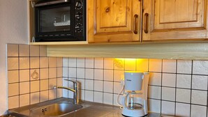 Une cuisine avec des meubles de rangement en bois, un four à micro-ondes, une machine à café et un évier.