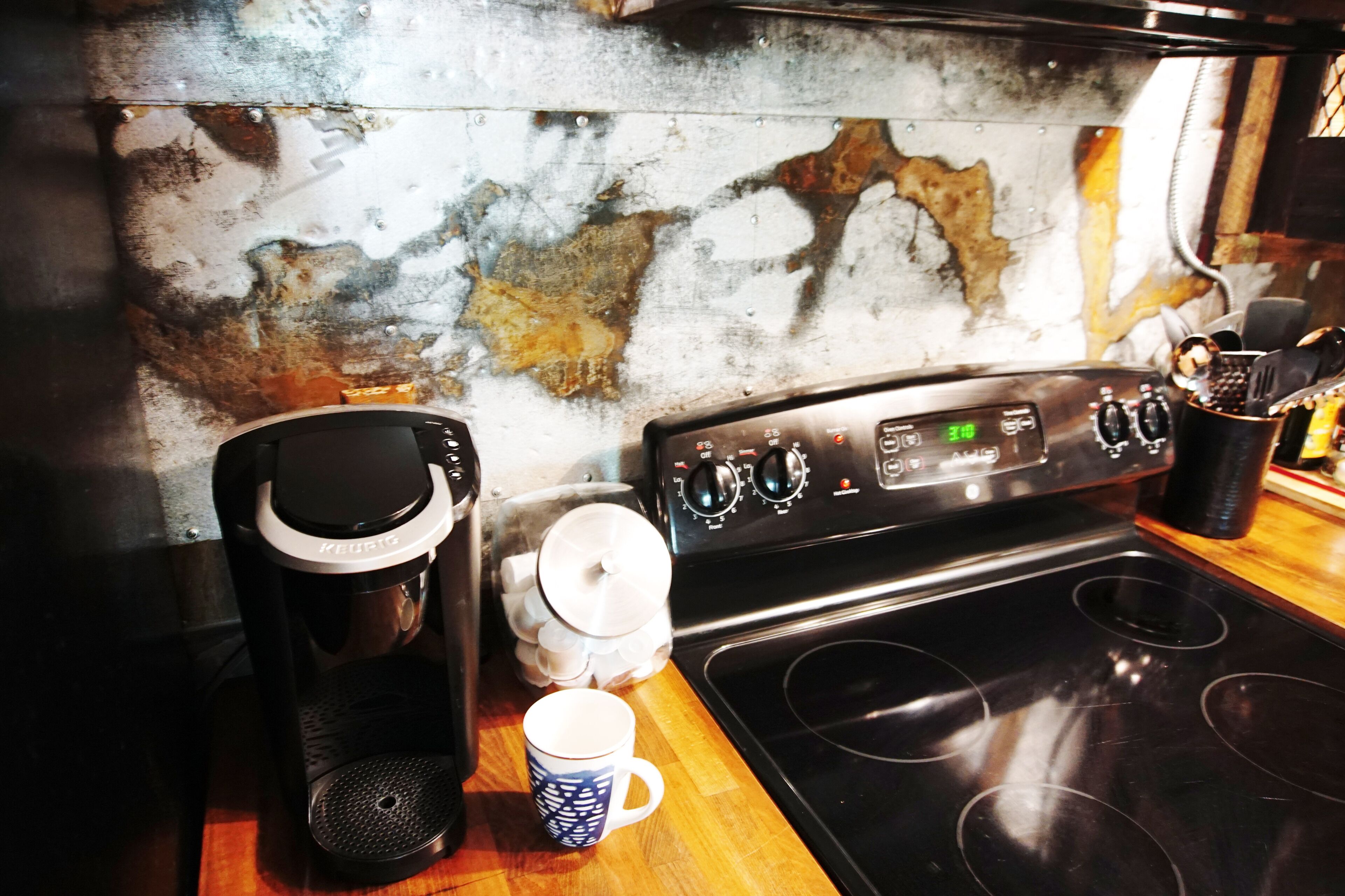 Una cocina con cafetera, taza y estufa.
