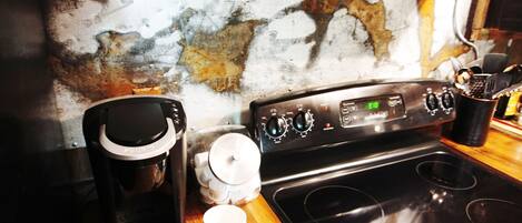 Una cocina con cafetera, taza y estufa.