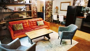 A cozy living room with a red leather sofa, a wooden coffee table, and two armchairs. - Industrial chic guesthouse (Tampa)