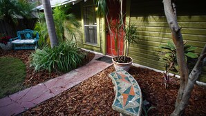 A house with a red door, a blue bench, and a potted plant in the front yard. - Industrial chic guesthouse (Tampa)