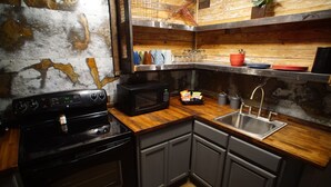 A kitchen with a black stove, a microwave, a sink, and wooden countertops. - Industrial chic guesthouse (Tampa)