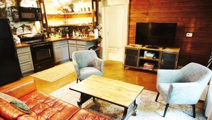 A living room with a red leather sofa, two armchairs, a wooden coffee table, and a television. - Industrial chic guesthouse (Tampa)