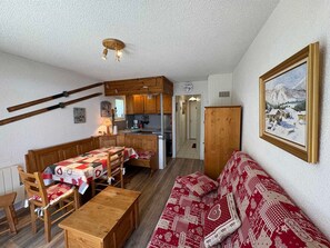 Una sala de estar acogedora con un sofá y una mesa de madera, una cocina con armarios de madera, y un comedor con una mesa y sillas.